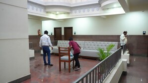 A lobby with a white sofa, a wooden chair, and a railing. - Sri Sai Residence (Tumkur)