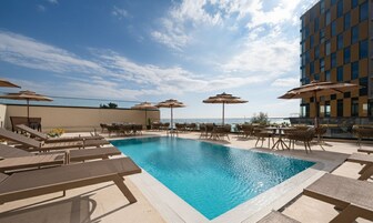 Una piscina al aire libre, sombrillas, sillones reclinables de piscina