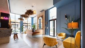A modern lobby with a reception desk, seating area, and large windows. - Hotel Invictus (Becici)