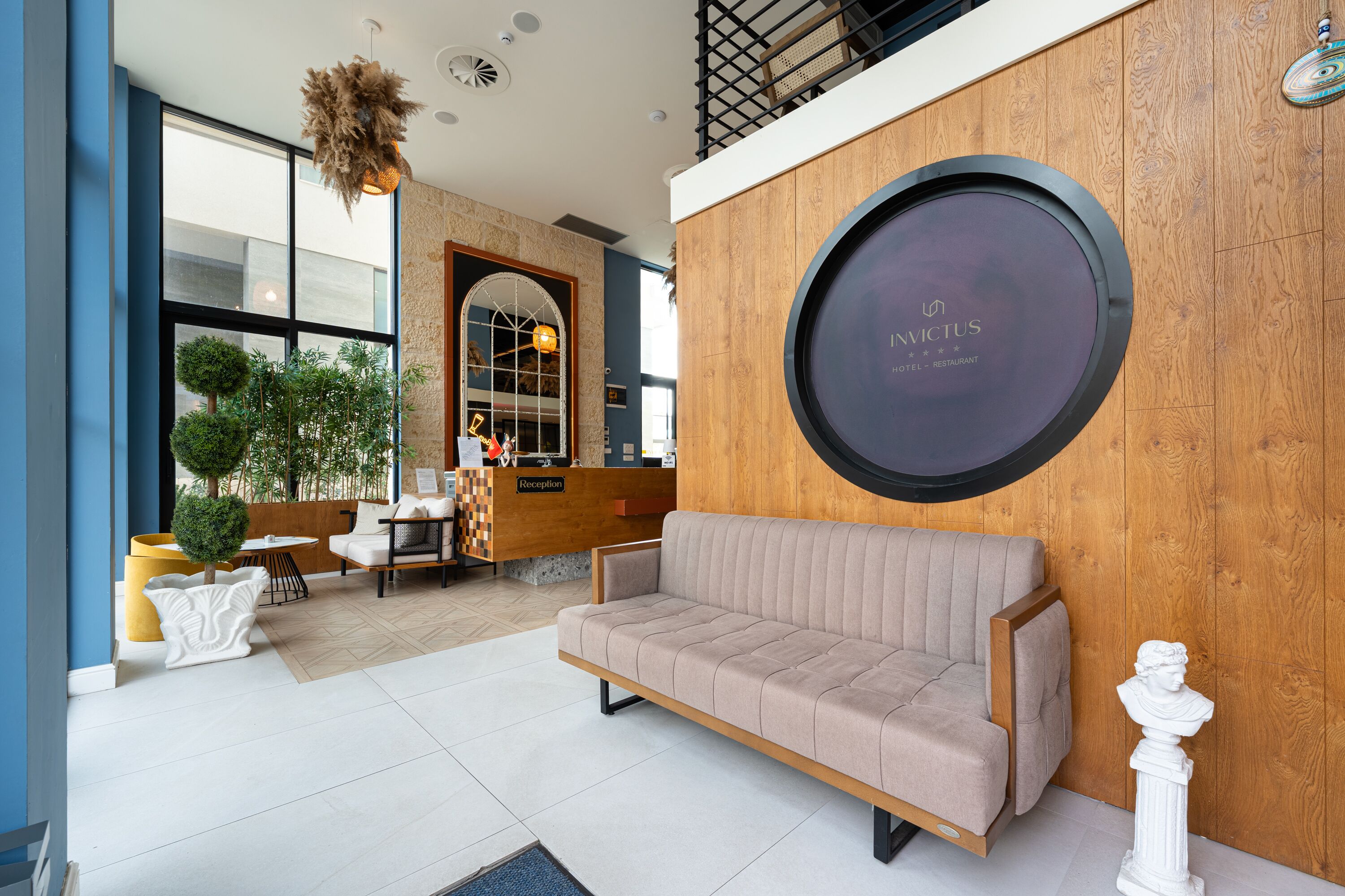 A modern hotel lobby with a reception desk, seating area, and a large circular sign on the wall.