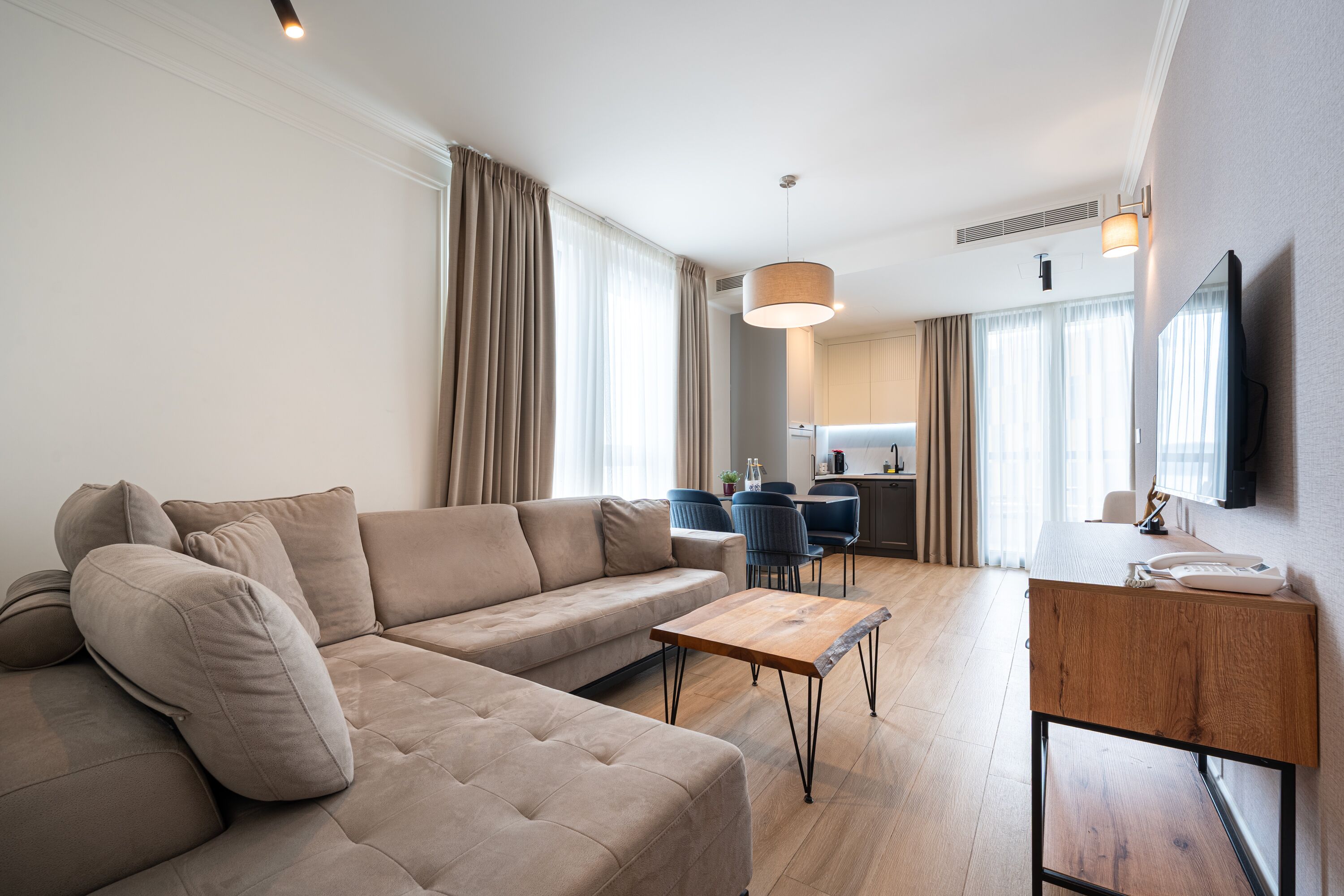 A modern living room with a sectional sofa, a wooden coffee table, and a TV on a wall-mounted stand.