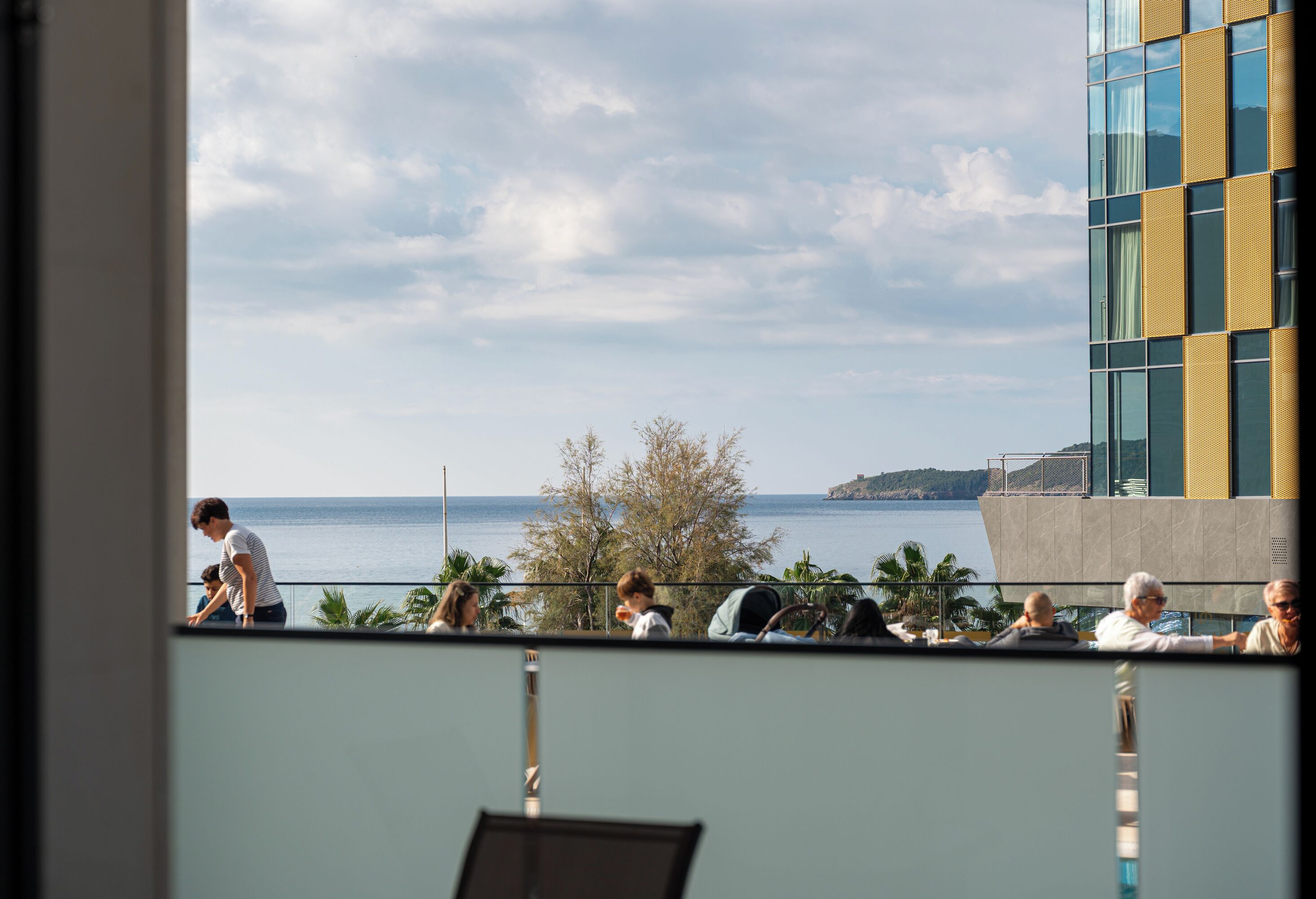 A view from a balcony overlooking a body of water with a modern building in the background.