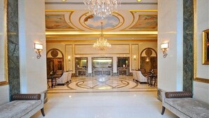 A luxurious lobby with a chandelier, marble floors, and seating areas. - Honu Hideaway Studio at Royal Garden | Lanai Oasis (Honolulu)