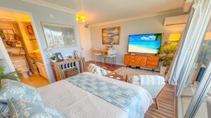 A bedroom with a large bed, a TV, a desk, and a chair. - Honu Hideaway Studio at Royal Garden | Lanai Oasis (Honolulu)