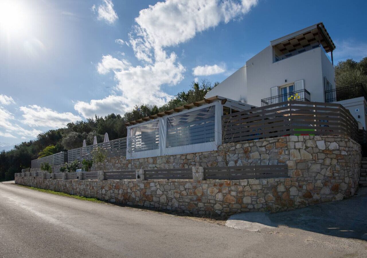 A modern building with a stone facade, a balcony, and a clear sky.