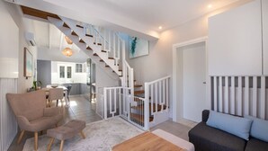Een moderne woonkamer met een trap, een eethoek en een keuken.