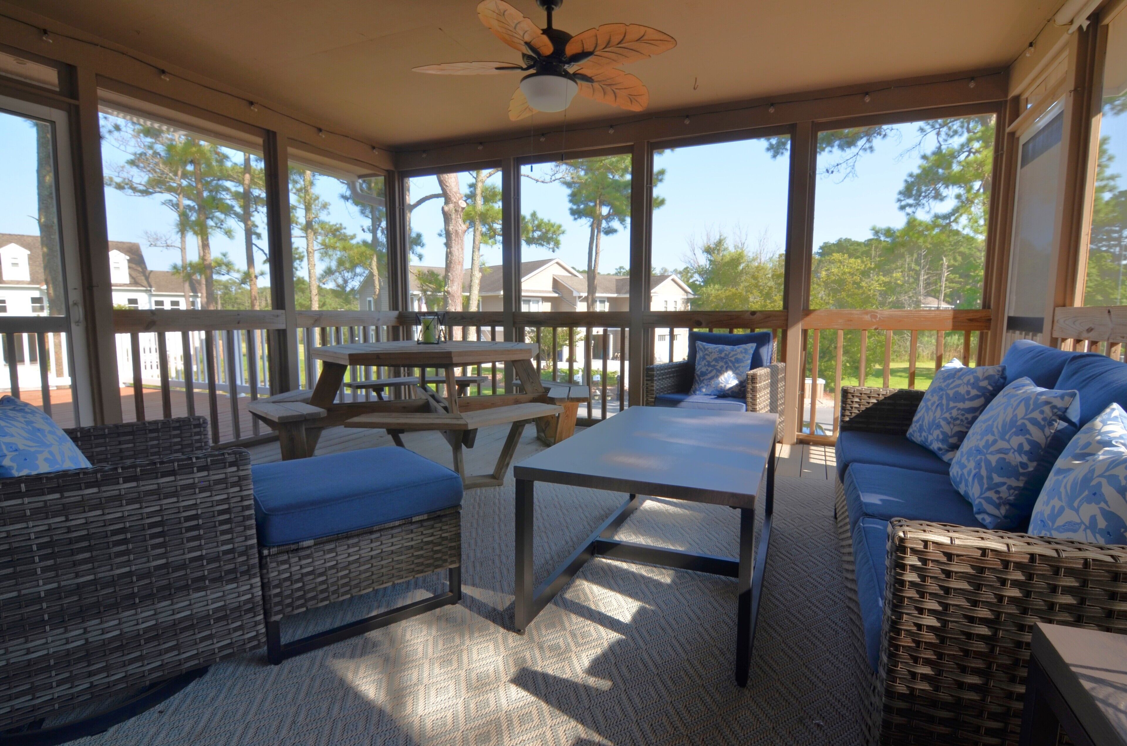A covered outdoor patio with wicker furniture, a table, and a ceiling fan.