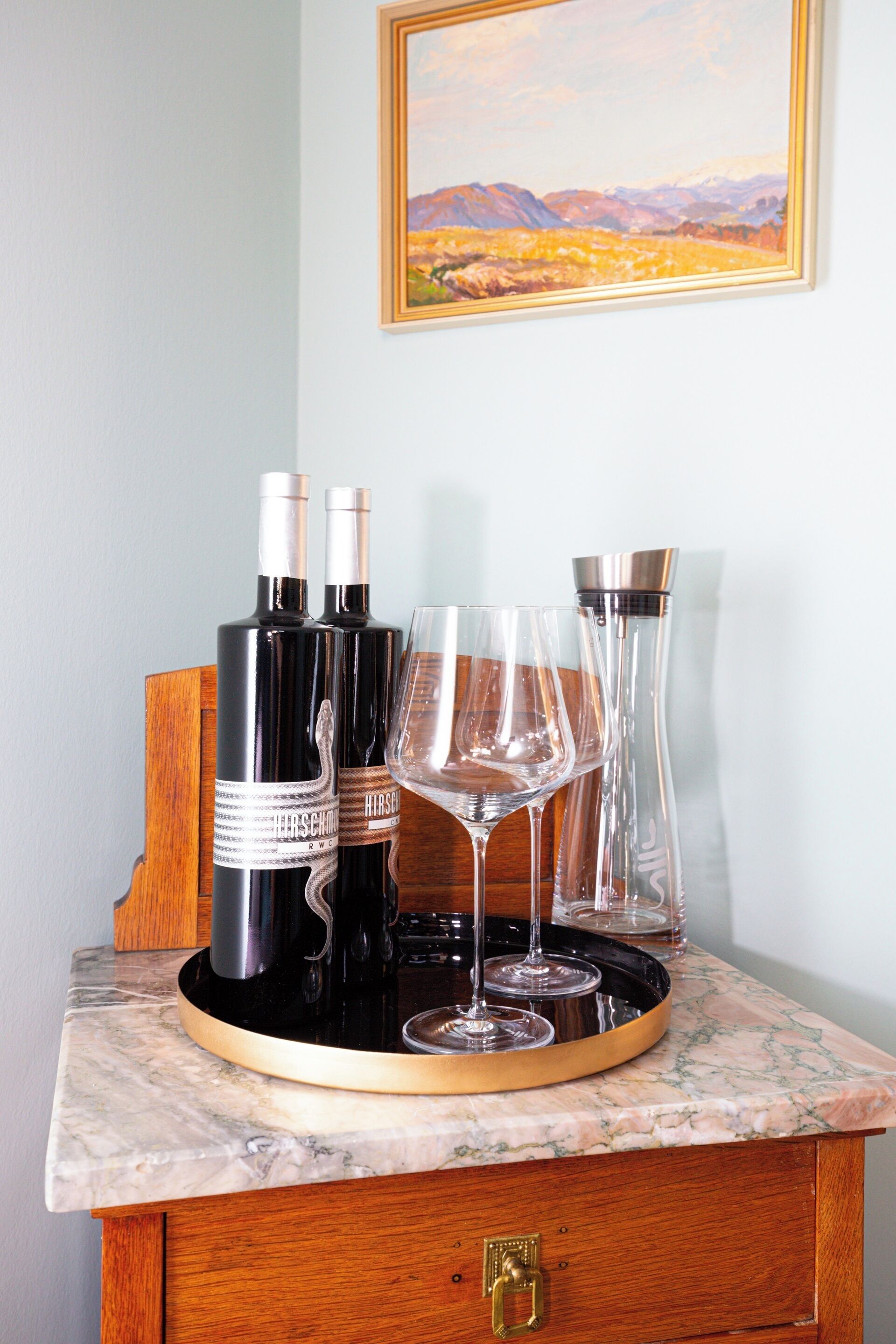 A wine and glass set on a marble countertop with a wooden cabinet below.