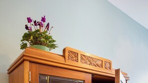 A wooden cabinet with glass doors, a marble countertop, and a tea set. - Penta Apartments (Gamlitz)