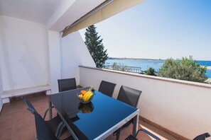 A balcony with a table and chairs, a bowl of fruit, and a view of the sea. - Studio Semy with Terrace and Sea View (Novalja)