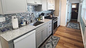 A modern kitchen with white cabinets, a tiled backsplash, and a wooden ceiling.