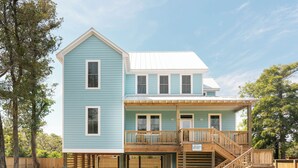 A two-story house with a covered porch and a wooden staircase leading to an upper level. - DC51: Walter's Watch - Brand New Construction (Ocracoke)