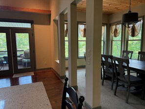 Amplia habitación con una mesa de comedor y sillas, ventanas grandes con cortinas y techo de madera.