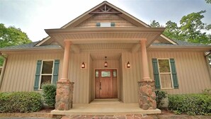 A two-story house with a front porch, stone pillars, and a wooden door.