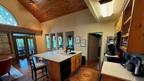 A spacious kitchen with wooden cabinets, a large island, and a view of the outdoors through the windows.