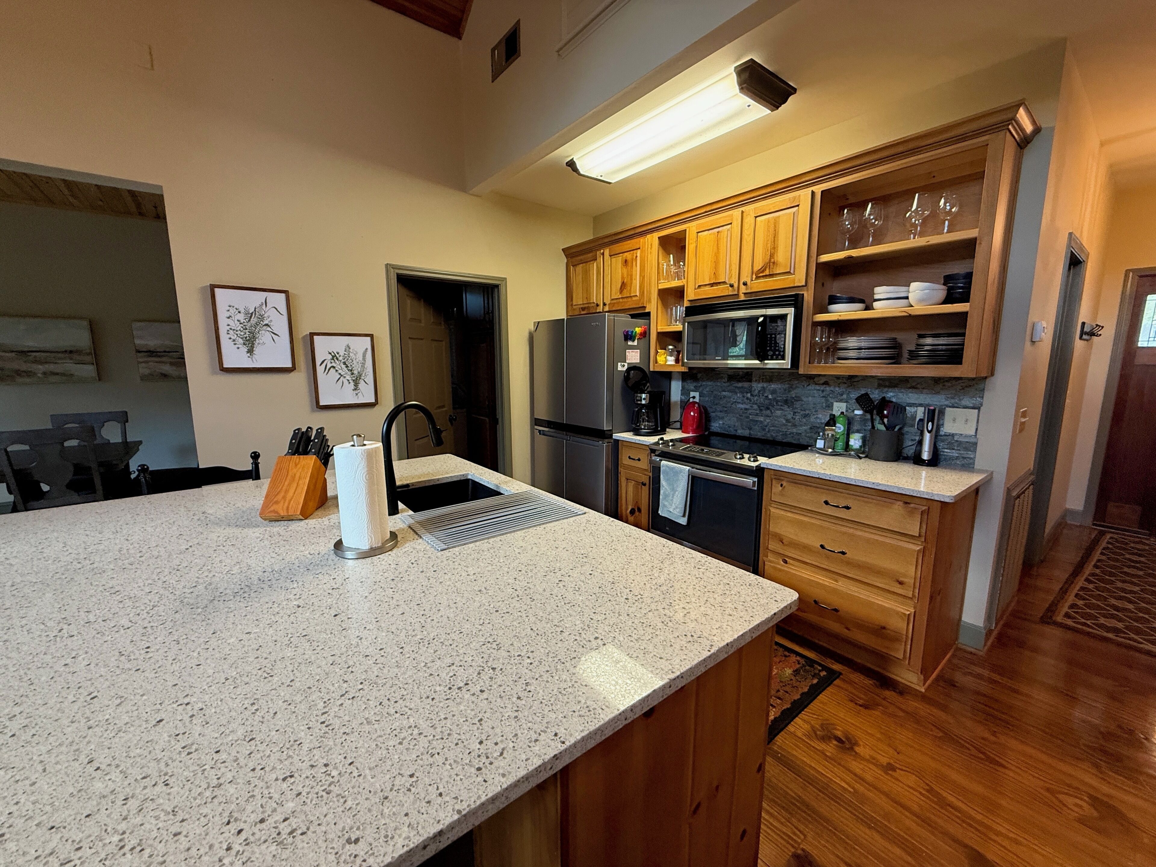 Una cocina con encimeras de granito, armarios de madera y electrodomésticos de acero inoxidable, además de una isla grande.