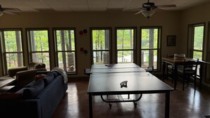 A spacious room with a large table, a sofa, and a ceiling fan.