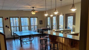 A spacious kitchen with a large island, bar stools, and a ping pong table.