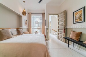 A modern hotel room with a large bed, a desk, and a view of the city.