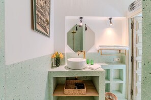 A bathroom with a round sink, a mirror, and a towel rack.