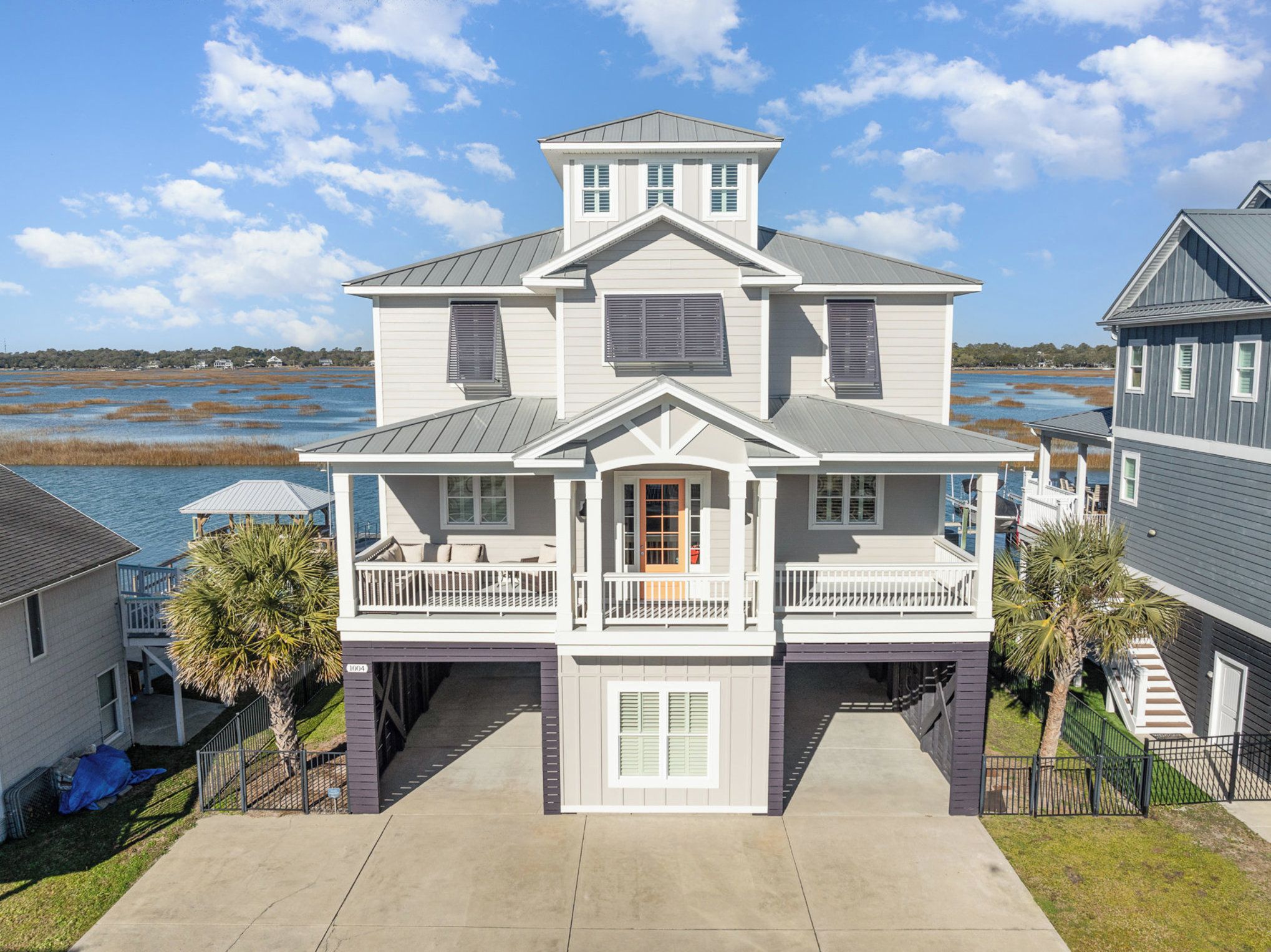 A two-story house with a balcony, a covered porch, and a view of a body of water.