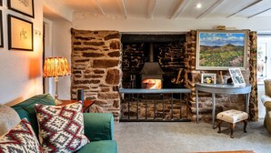 A cozy living room with a stone fireplace, a green sofa, and a table with a lamp. - Whitley (Molland)
