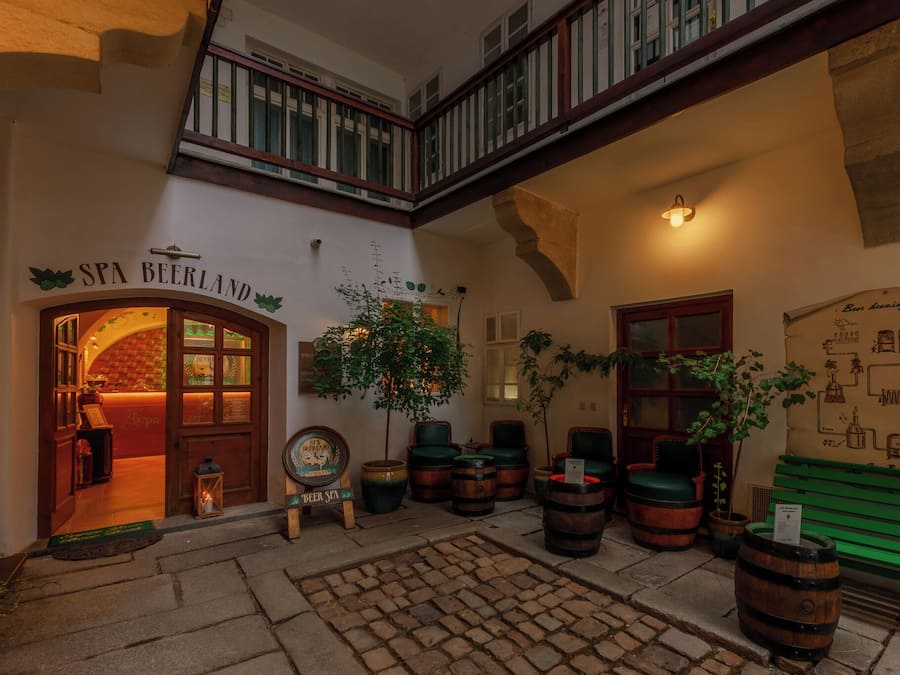 Un interior acogedor con un letrero que dice "SPA BEERLAND", barriles de madera y un banco verde.
