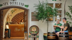 Una entrada acogedora a SPA BEERLAND, con un arco de madera, una señal y dos barriles de madera.