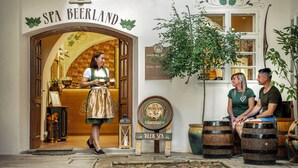 Entrada a un spa Beerland, con un letrero, un área de asientos con barriles de madera y una persona de pie en el umbral.