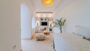 A bedroom with a large bed, a TV, and a seating area with a plant. - Riad Ines 10min from the medina - Swimming pool - Breakfast (Marrakech)