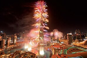 A nighttime cityscape with a prominent skyscraper and fireworks.