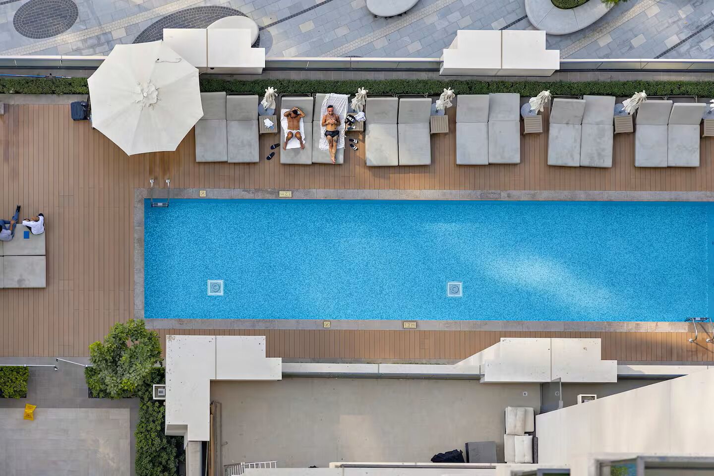 Un espace piscine aménagé sur le toit, avec des chaises longues et un grand parasol.