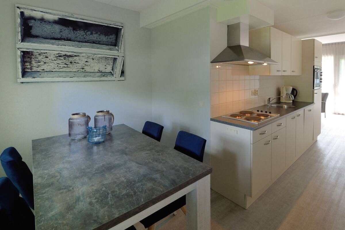 A modern kitchen with a dining table, chairs, and a stove.