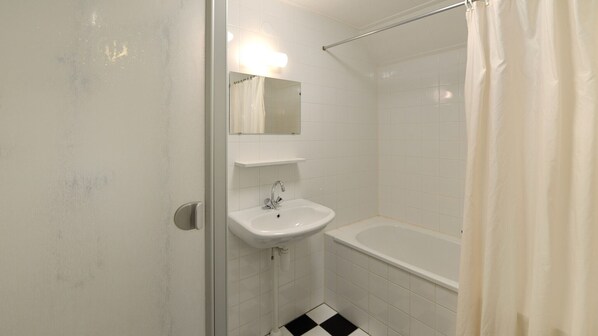 A bathroom with a white sink, a mirror, and a shower area.