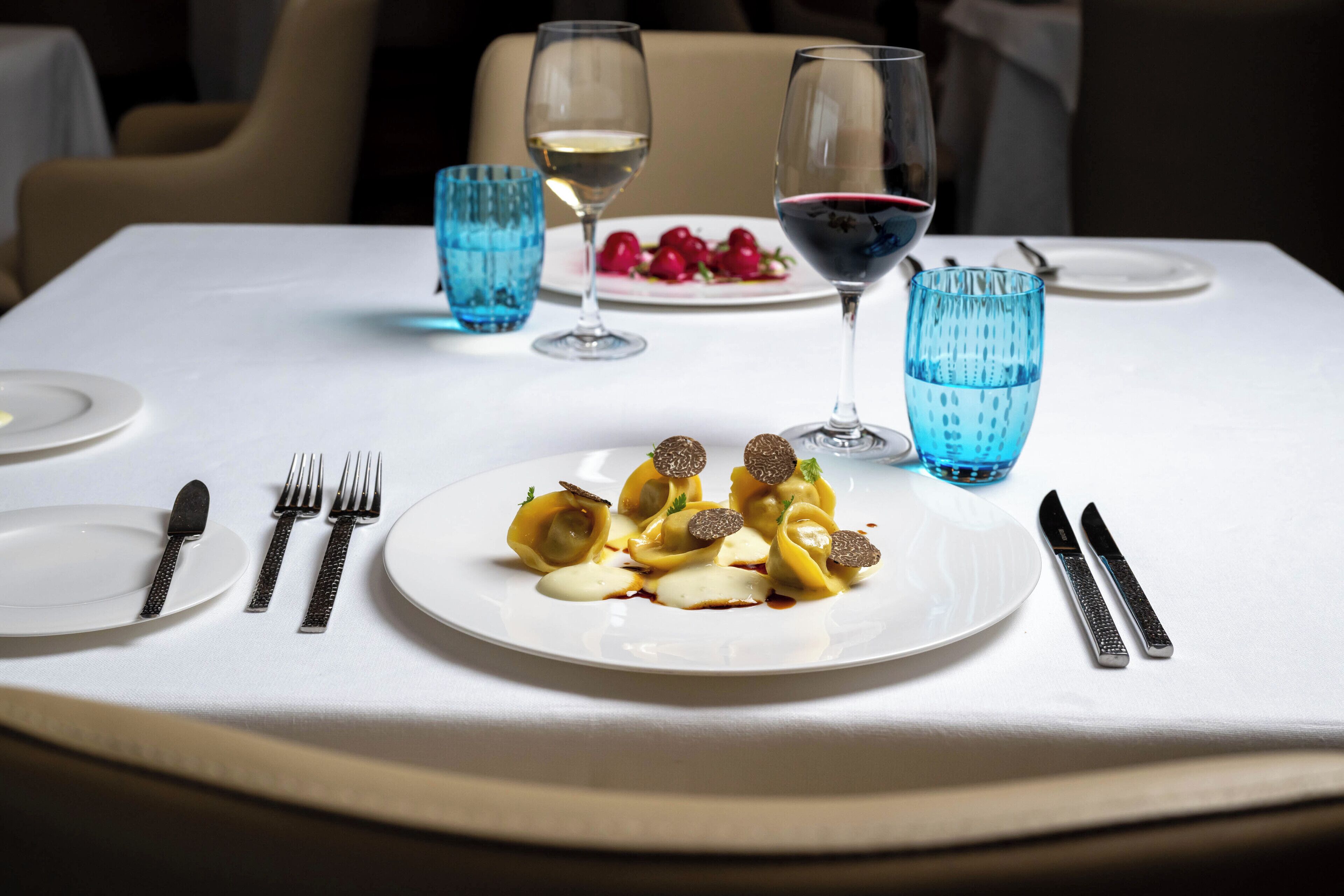 A dining table set with plates, cutlery, and glasses.