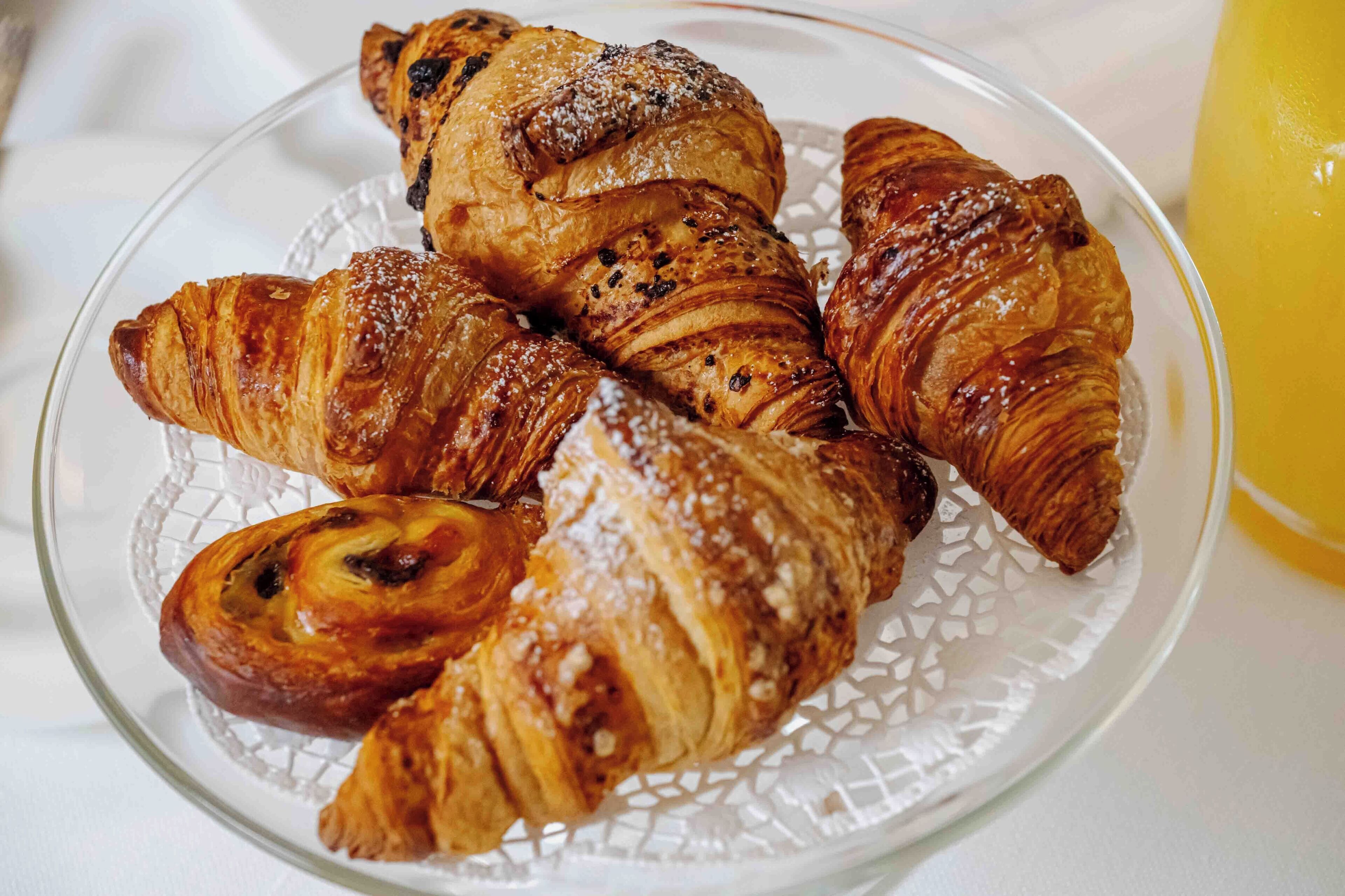 A glass plate with croissants and a glass of orange juice.