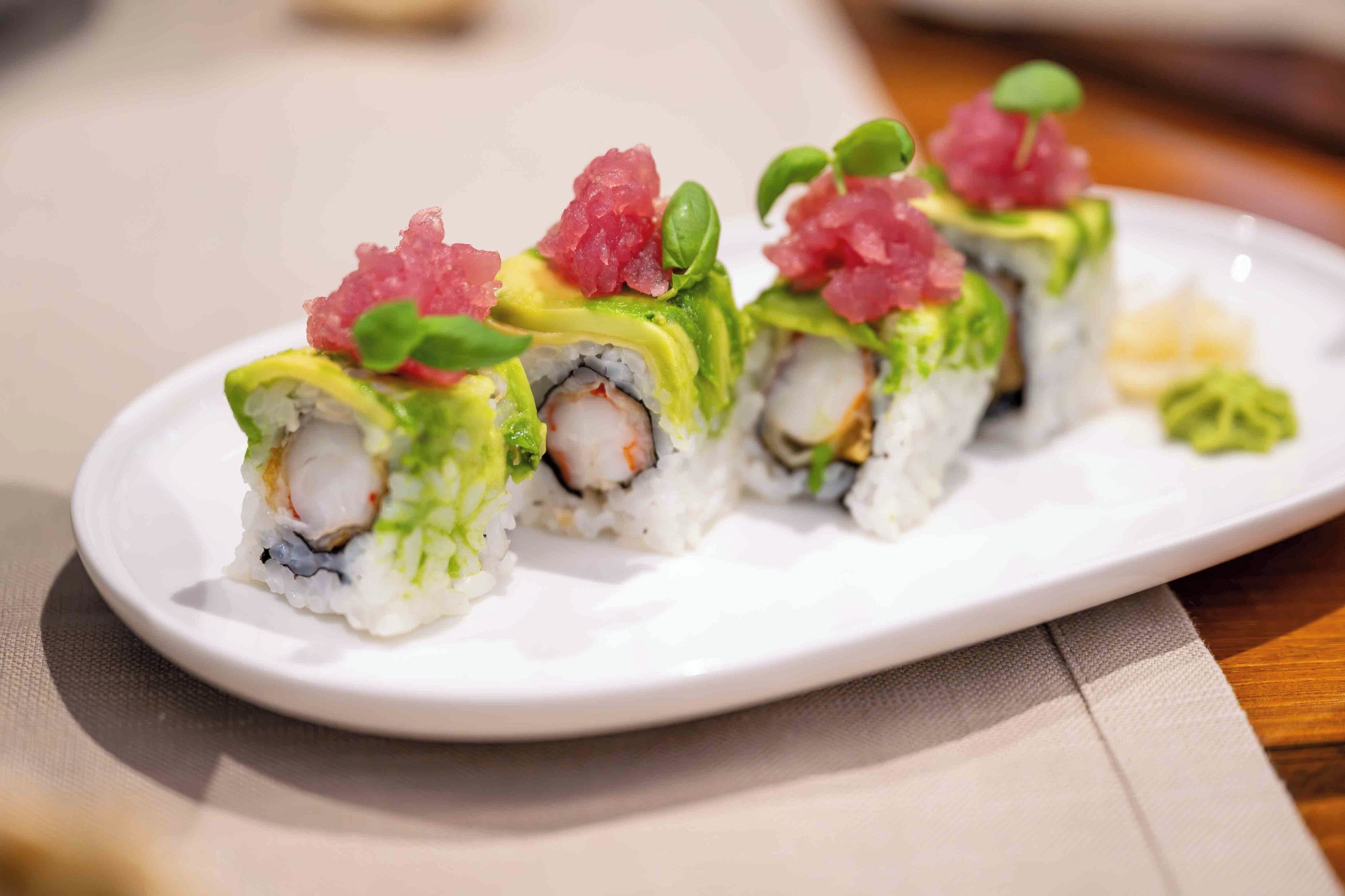 A plate of sushi with avocado and fish toppings.