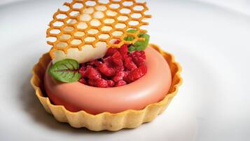 A dessert with a lattice top, a creamy base, and raspberries.