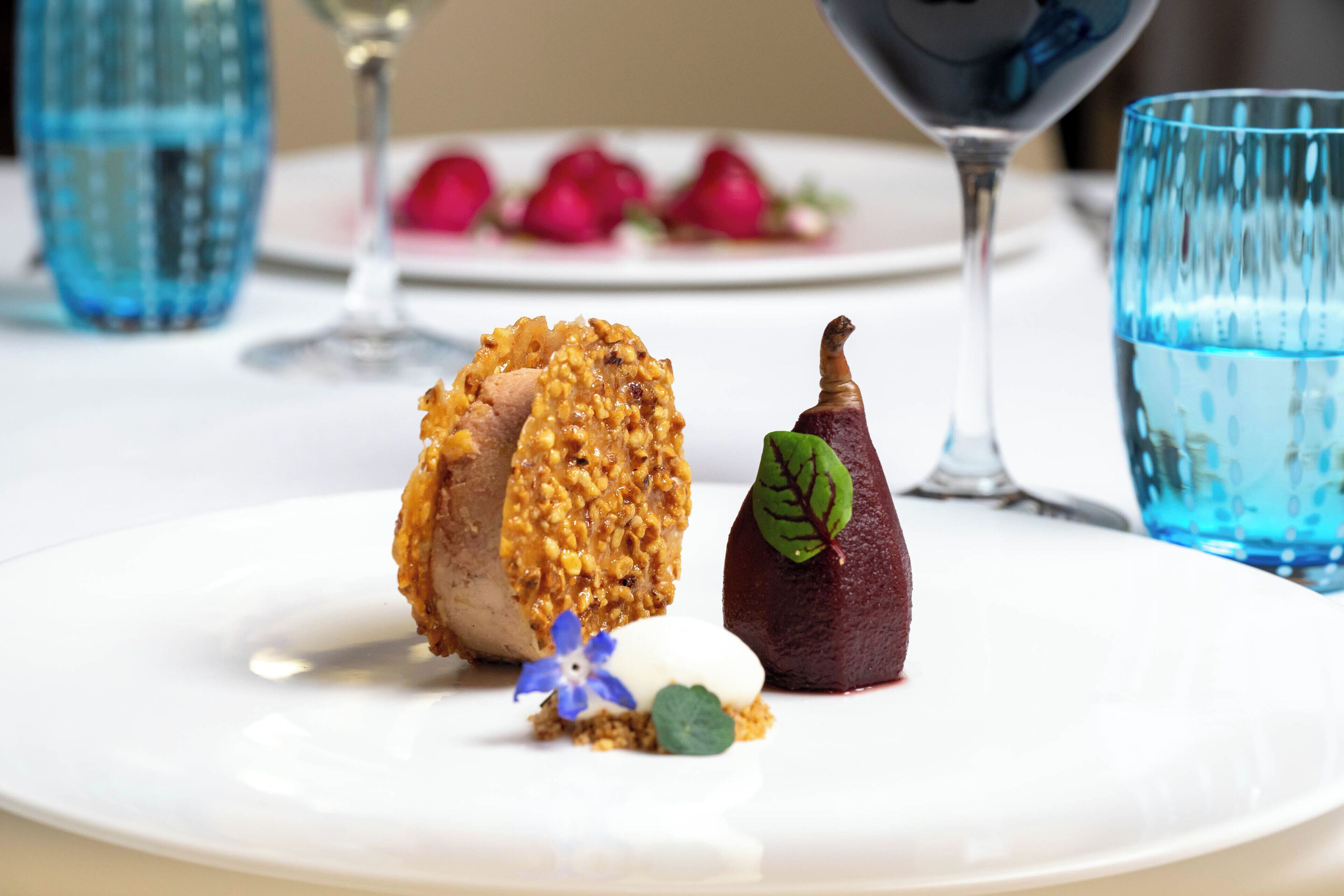 Une assiette à dessert avec une part de gâteau, une baie et une petite fleur.