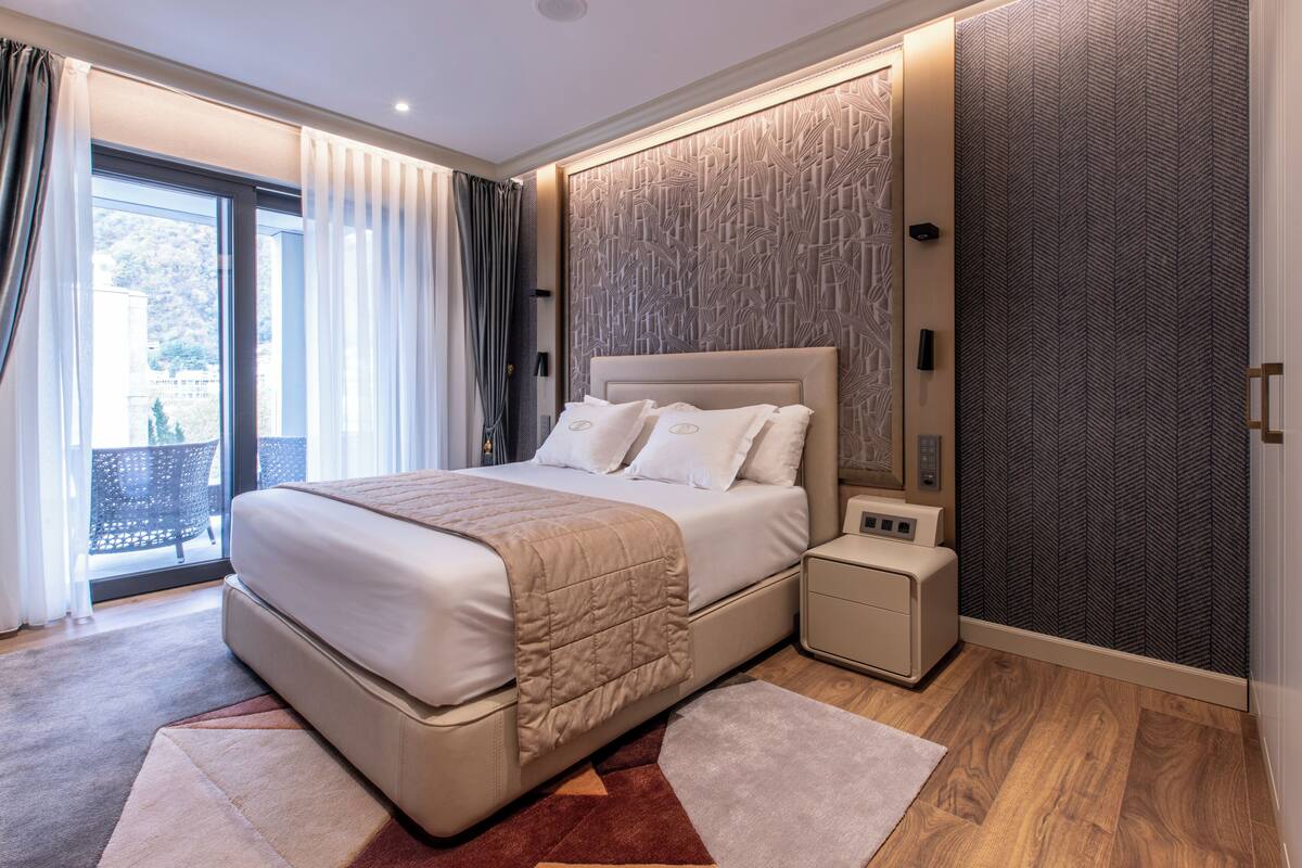A modern bedroom with a large bed, a nightstand, and a wardrobe.