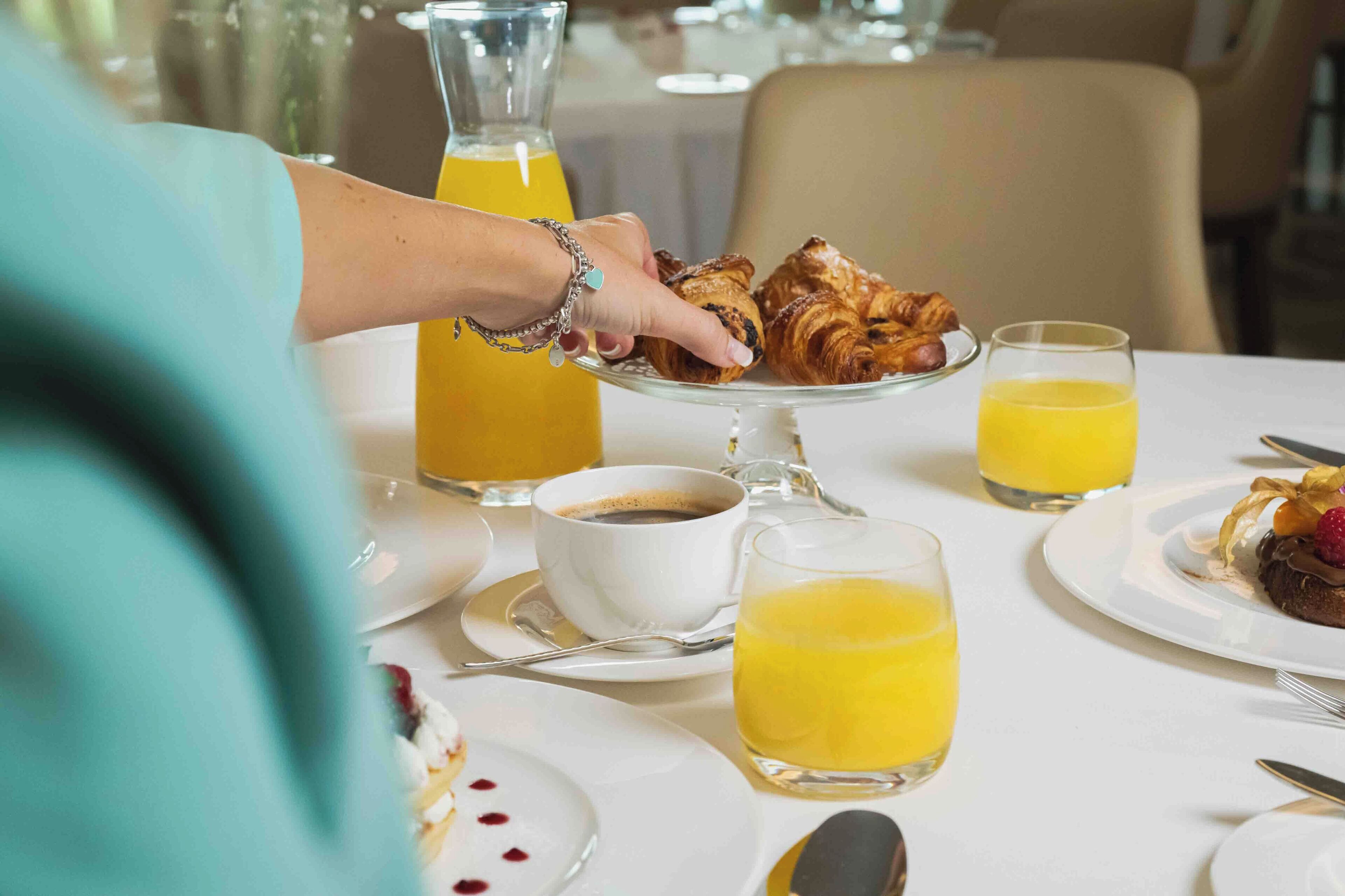 Ein Frühstückstisch mit Croissants, Kaffee und Orangensaft.