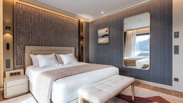 Een moderne slaapkamer met een groot bed, nachtkastjes, een bankje, een spiegel en uitzicht op de bergen door het raam.