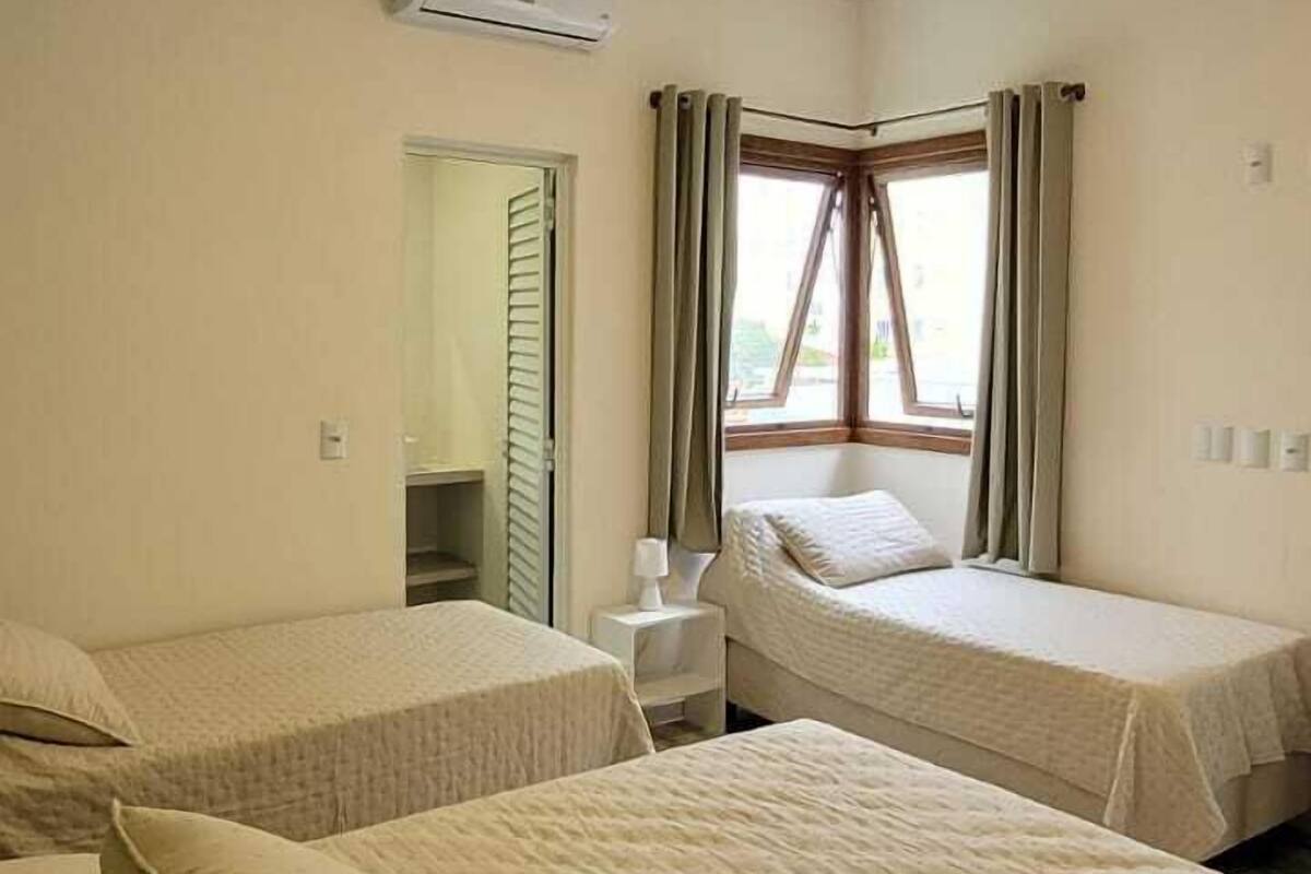 Una camera d'albergo con due letti, una scrivania e una finestra con tende.