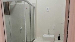 A bathroom with a glass-enclosed shower, a white sink, and a toilet. - La Casona (Florianópolis)