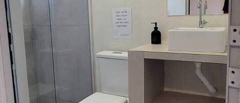 A modern bathroom with a glass shower enclosure, a white toilet, and a vanity with a mirror.