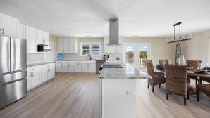A spacious kitchen with white cabinets, stainless steel appliances, and a central island.