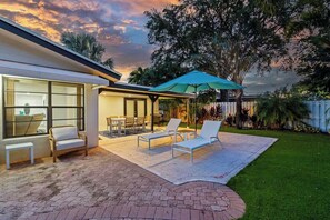 Un espace patio aménagé avec du mobilier d’extérieur, un coin salon couvert et une vue sur le jardin arrière.