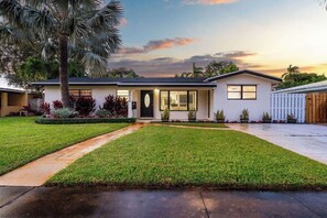 Une maison à deux étages avec une pelouse bien entretenue, une porte d’entrée et un garage.