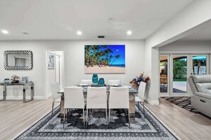 A modern dining area with a glass table, white chairs, and a black and white patterned rug. - Tropical Getaway | Heated Pool & Patio Retreat (Fort Lauderdale)