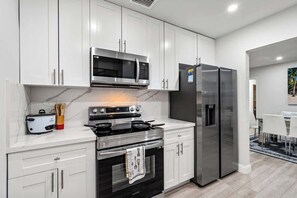 A modern kitchen with white cabinets, stainless steel appliances, and a marble countertop. - Tropical Getaway | Heated Pool & Patio Retreat (Fort Lauderdale)